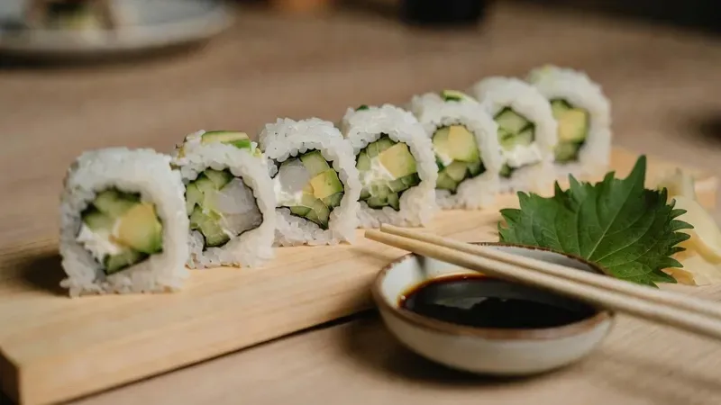 A couple rolling sushi together at a beginner sushi making class in Brooklyn NYC with a chef instructor guiding them